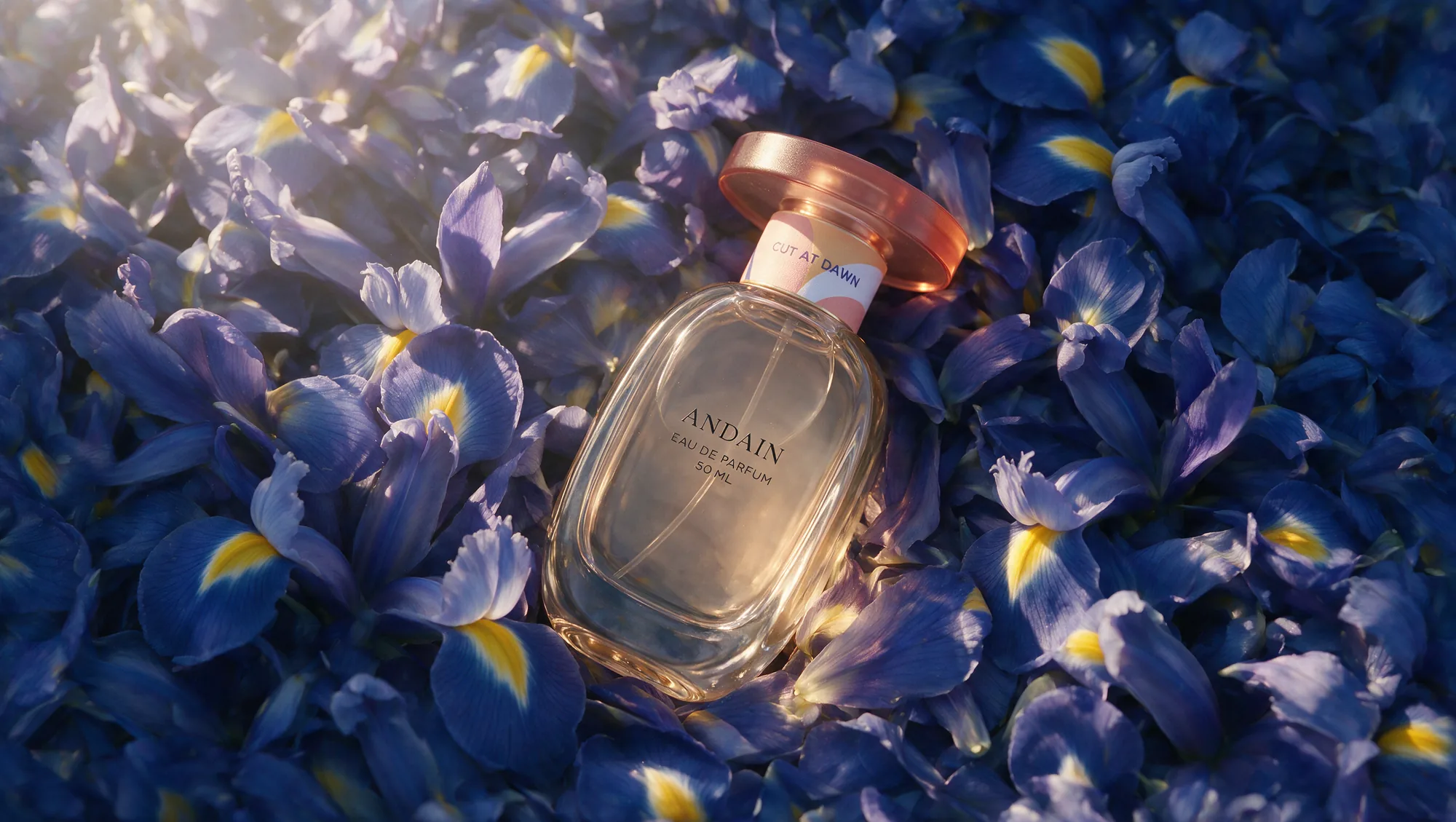 The bottle laid on a dense bed of blue iris petals, seen from above.