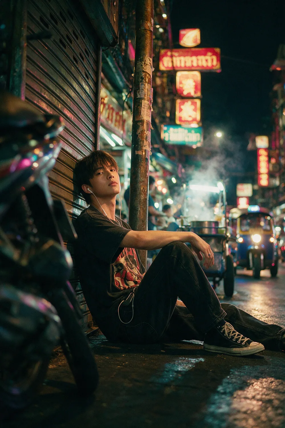 Sitting against a metal shutter, the street lit behind.